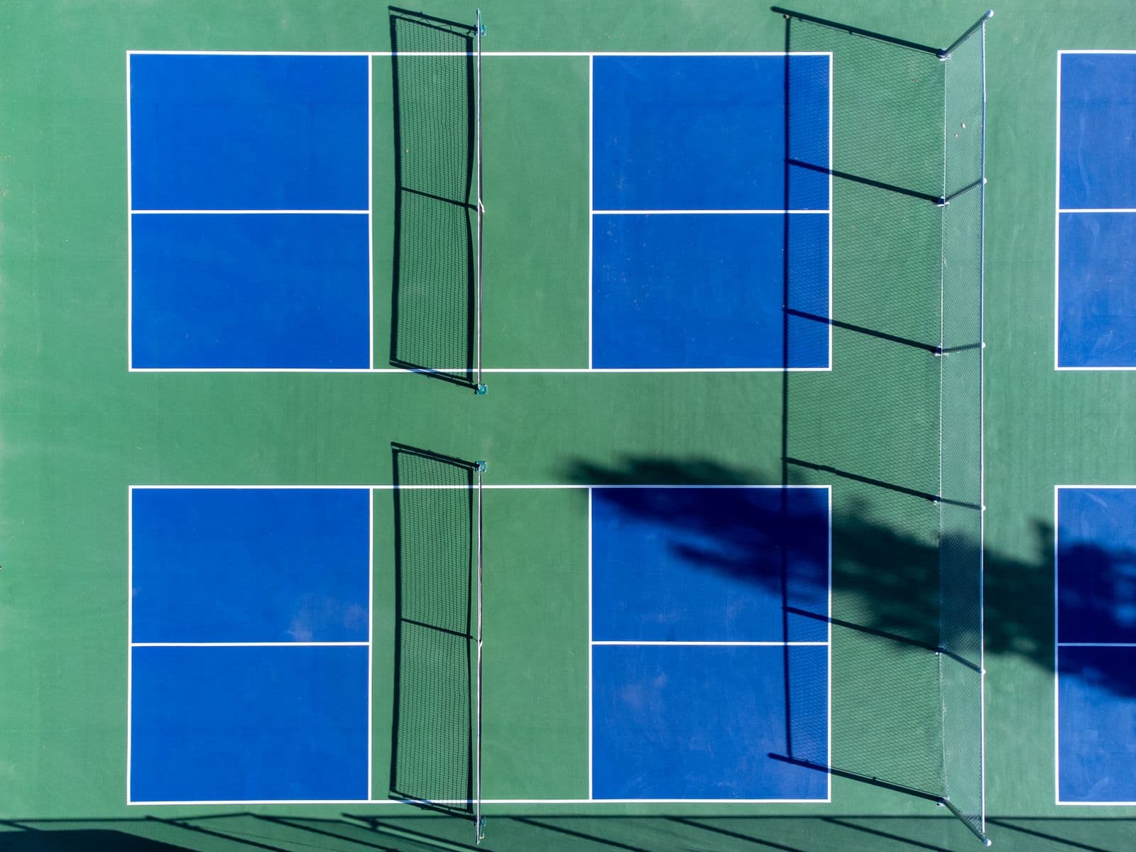 Vue aérienne de terrains de pickleball bleus et verts avec leurs filets